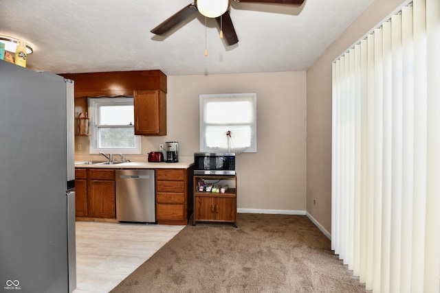 kitchen with stainless steel appliances, ceiling fan, light colored carpet, and sink