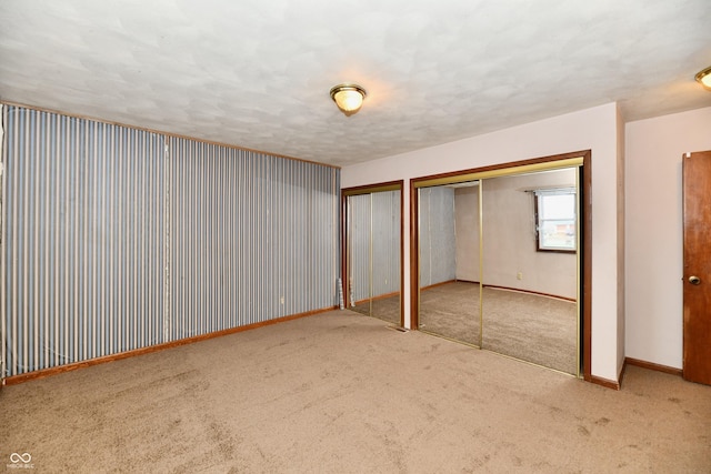 unfurnished bedroom featuring multiple closets and carpet