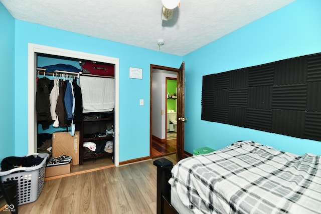 bedroom with hardwood / wood-style floors, a textured ceiling, a closet, and ceiling fan