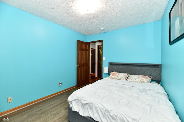 bedroom with dark hardwood / wood-style floors and a textured ceiling