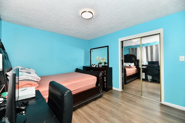 bedroom with a closet, light hardwood / wood-style floors, and a textured ceiling