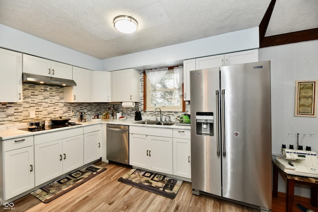 kitchen featuring sink, stainless steel appliances, a textured ceiling, white cabinets, and light wood-type flooring