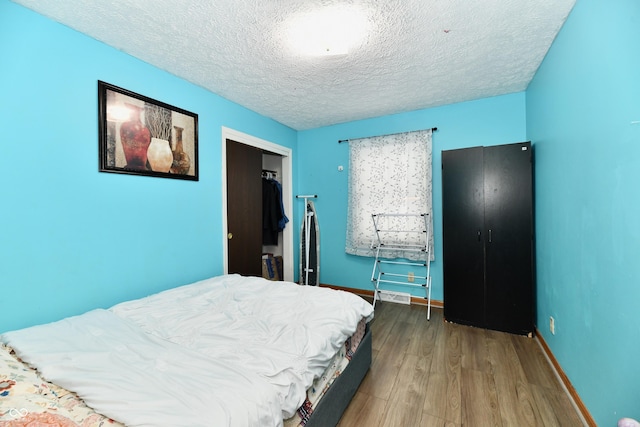 bedroom featuring a closet, wood-type flooring, and a textured ceiling