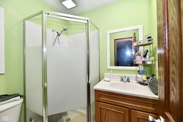 bathroom featuring a shower with door, vanity, and toilet