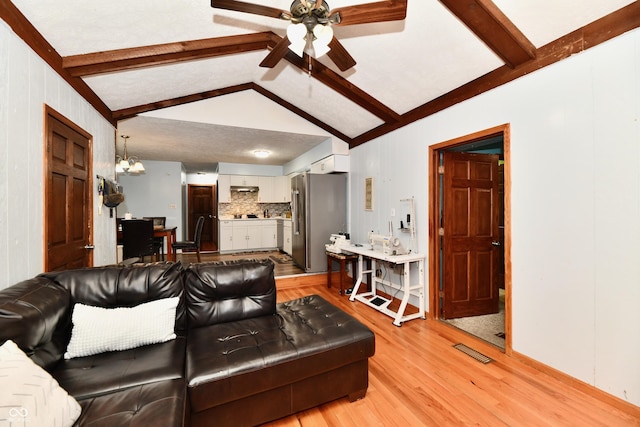 living room with ceiling fan with notable chandelier, vaulted ceiling with beams, and light hardwood / wood-style floors