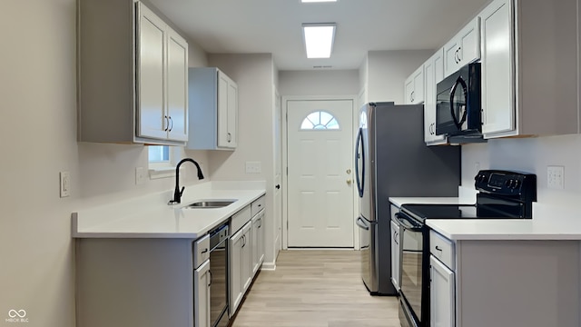 kitchen featuring white cabinetry, sink, light hardwood / wood-style floors, and black appliances