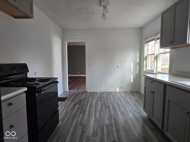 kitchen with a textured ceiling, gray cabinets, dark wood-type flooring, and black / electric stove