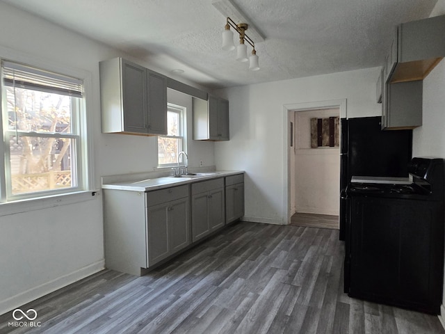 kitchen with a textured ceiling, gray cabinets, sink, and black electric range