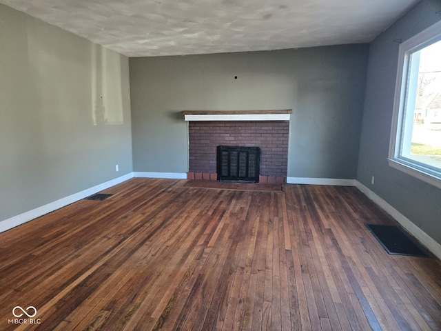 unfurnished living room featuring a wealth of natural light, a fireplace, and dark hardwood / wood-style floors