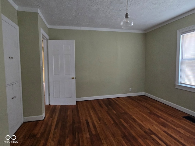 empty room featuring crown molding, dark wood-type flooring, and a textured ceiling