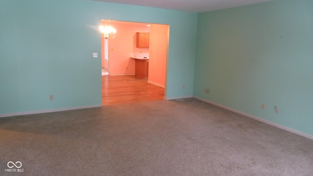 carpeted empty room with a notable chandelier