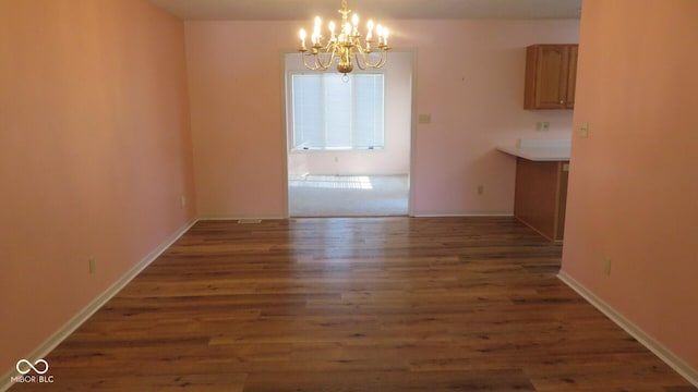 unfurnished dining area featuring dark hardwood / wood-style flooring and a notable chandelier