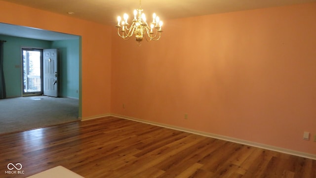 empty room with wood-type flooring and a chandelier