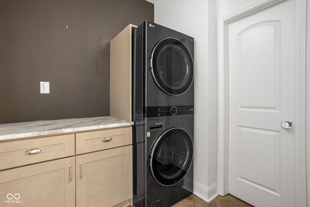 laundry area featuring stacked washer / dryer, light parquet flooring, and cabinets