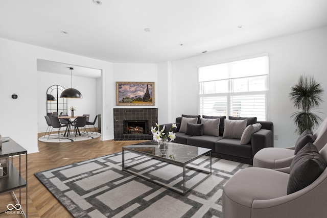 living room with light parquet flooring and a tiled fireplace