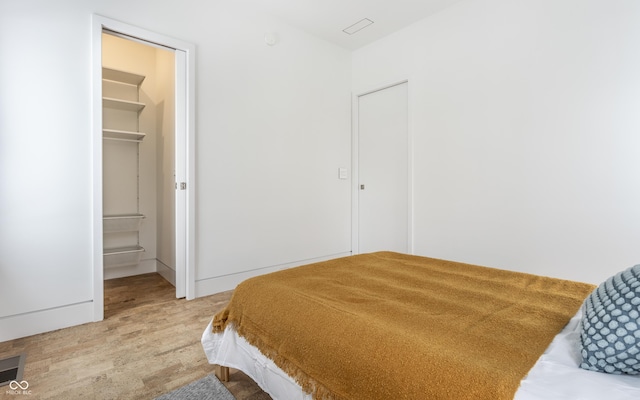 bedroom with hardwood / wood-style floors, a walk in closet, ensuite bath, and a closet