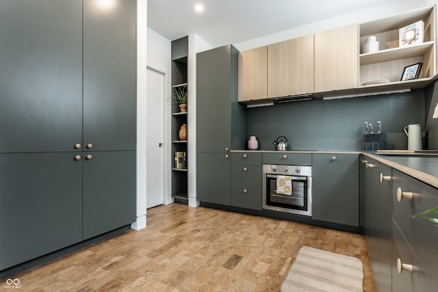 kitchen featuring stovetop, light brown cabinetry, and stainless steel oven