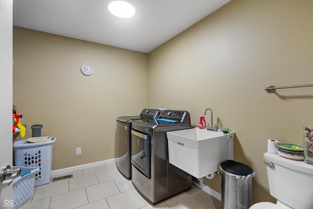 laundry room with sink, light tile patterned floors, and washer and dryer