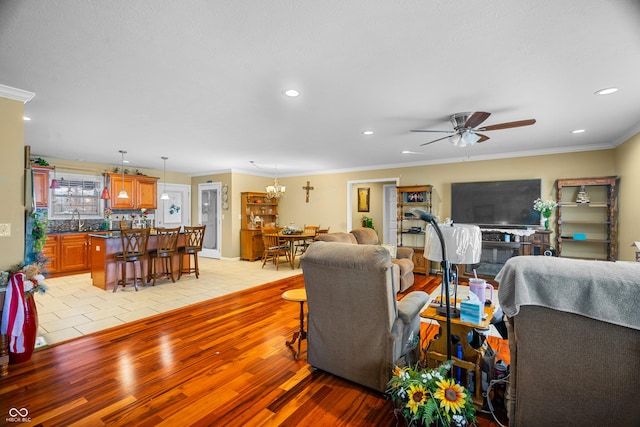 living room with crown molding, sink, ceiling fan, and light hardwood / wood-style floors