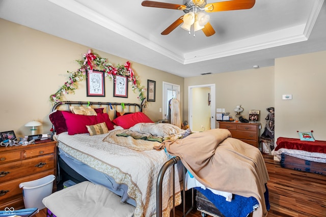 bedroom featuring a raised ceiling, ceiling fan, hardwood / wood-style floors, and ornamental molding