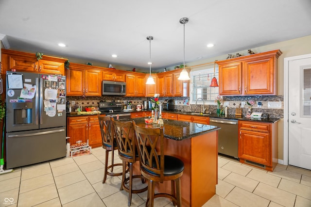 kitchen with sink, a center island, decorative light fixtures, light tile patterned flooring, and appliances with stainless steel finishes