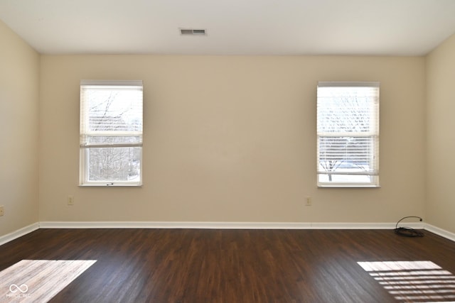 empty room with dark wood-type flooring and plenty of natural light