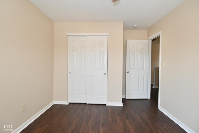 unfurnished bedroom with dark hardwood / wood-style flooring and a closet