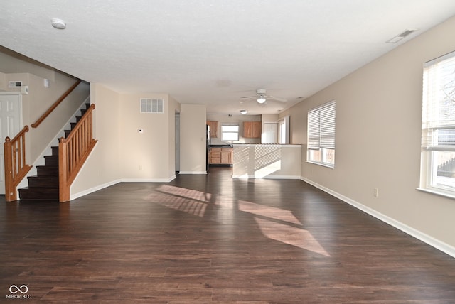 unfurnished living room featuring plenty of natural light, dark hardwood / wood-style floors, and ceiling fan