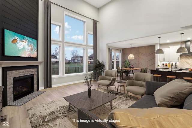 living room featuring light hardwood / wood-style flooring, a brick fireplace, a towering ceiling, and plenty of natural light