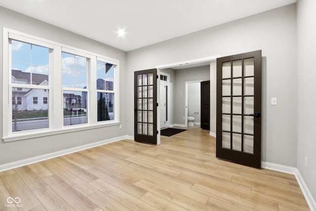 unfurnished room featuring french doors, a healthy amount of sunlight, and light hardwood / wood-style floors