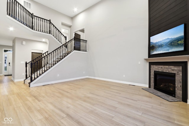 unfurnished living room featuring light hardwood / wood-style floors and a high ceiling