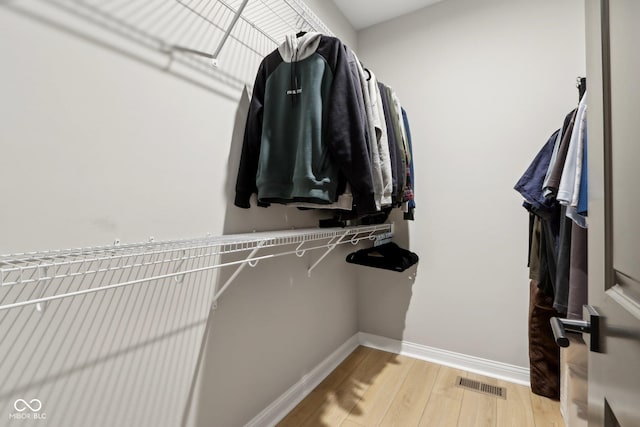 walk in closet with light hardwood / wood-style flooring