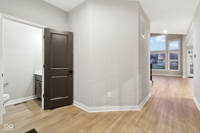 hallway with vaulted ceiling and light wood-type flooring