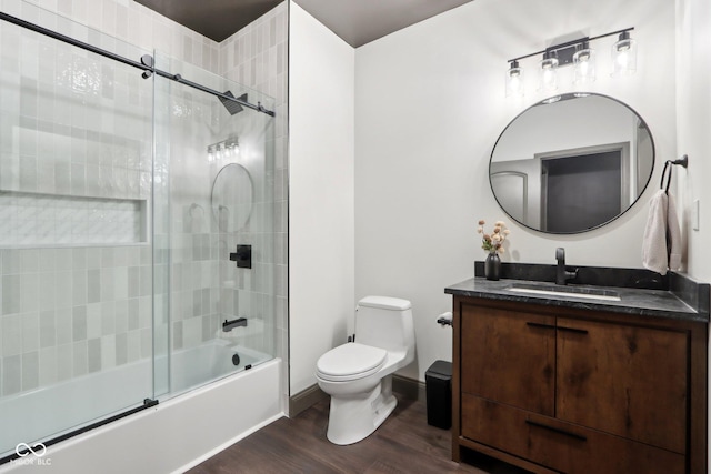 full bathroom featuring hardwood / wood-style flooring, vanity, shower / bath combination with glass door, and toilet