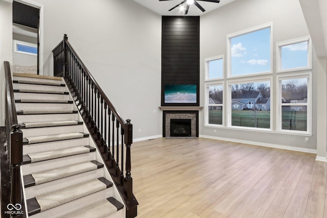 interior space with hardwood / wood-style floors, a fireplace, ceiling fan, and a high ceiling