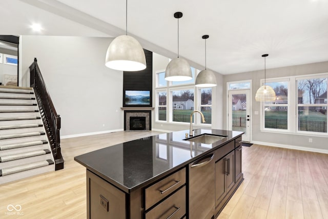 kitchen with dishwasher, sink, a kitchen island with sink, and decorative light fixtures