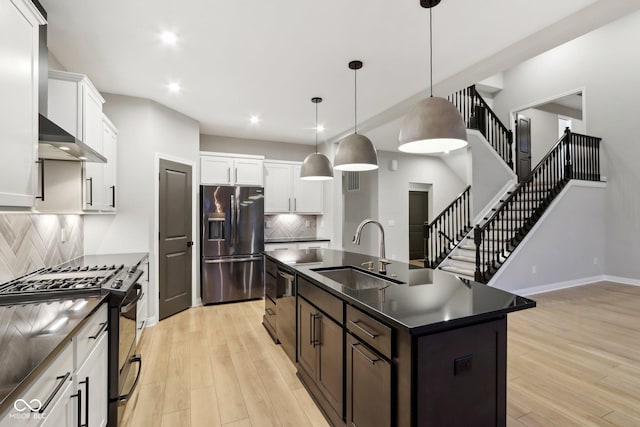 kitchen featuring sink, range with gas cooktop, a center island with sink, stainless steel fridge, and decorative backsplash