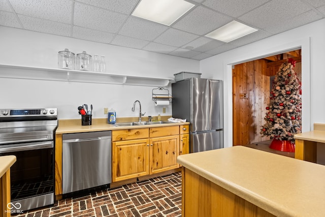 kitchen with a drop ceiling, sink, and appliances with stainless steel finishes