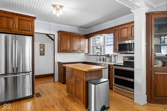 kitchen with decorative backsplash, wooden counters, stainless steel appliances, sink, and light hardwood / wood-style flooring