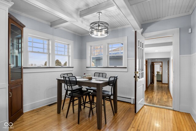 dining area with a chandelier, beam ceiling, light hardwood / wood-style flooring, and ornamental molding