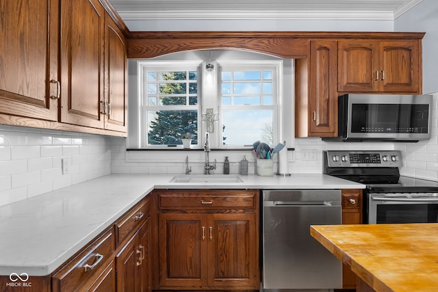 kitchen featuring sink, ornamental molding, tasteful backsplash, butcher block counters, and stainless steel appliances