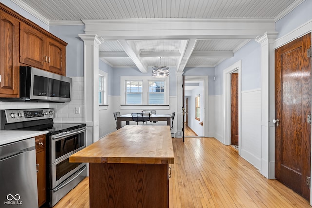 kitchen featuring wood counters, backsplash, beam ceiling, appliances with stainless steel finishes, and a kitchen island