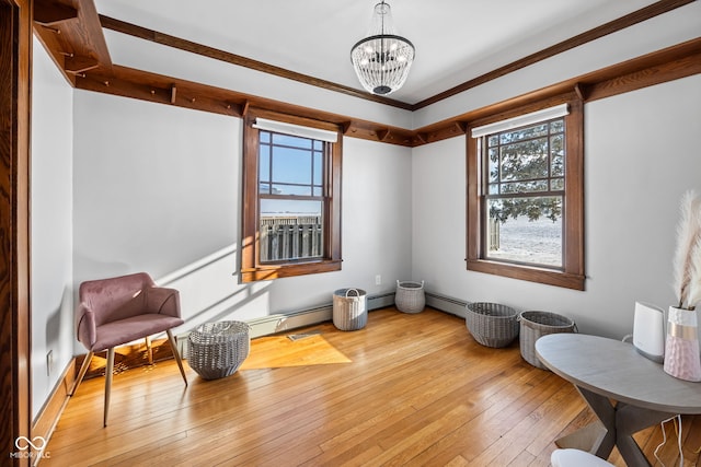 sitting room with wood-type flooring, an inviting chandelier, ornamental molding, and a baseboard heating unit