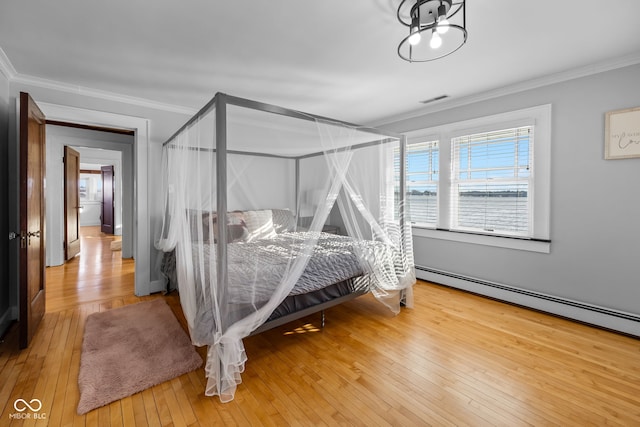 bedroom with wood-type flooring, a baseboard heating unit, and crown molding