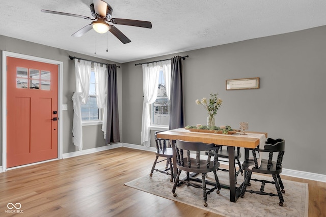 dining area with a textured ceiling, a ceiling fan, light wood-style flooring, and baseboards