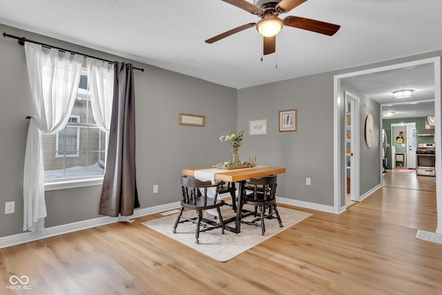 dining space featuring light wood-type flooring, ceiling fan, and baseboards