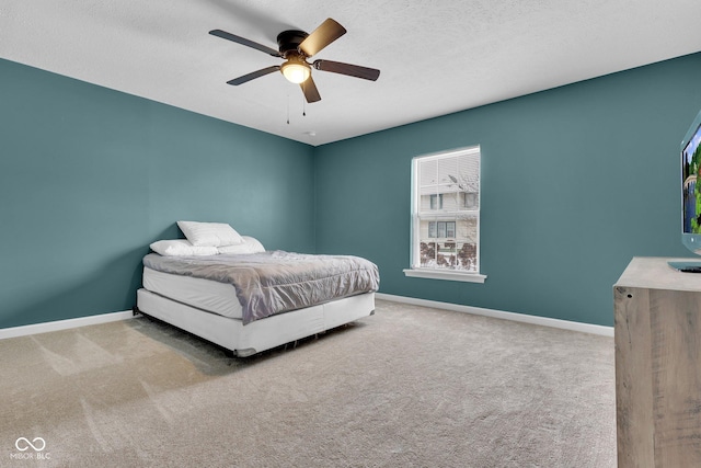 carpeted bedroom featuring ceiling fan, baseboards, and a textured ceiling