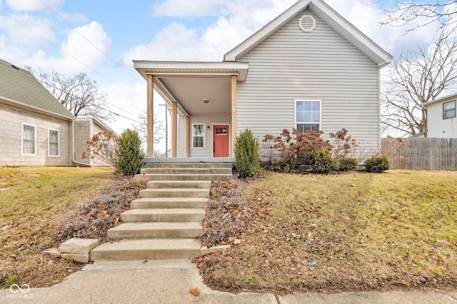 view of front of property with a porch, fence, and a front lawn