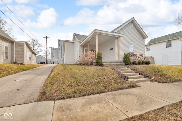 view of front of home with a front yard, covered porch, and driveway