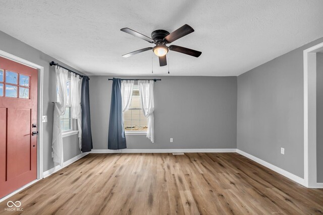 spare room featuring a textured ceiling, ceiling fan, wood finished floors, and baseboards